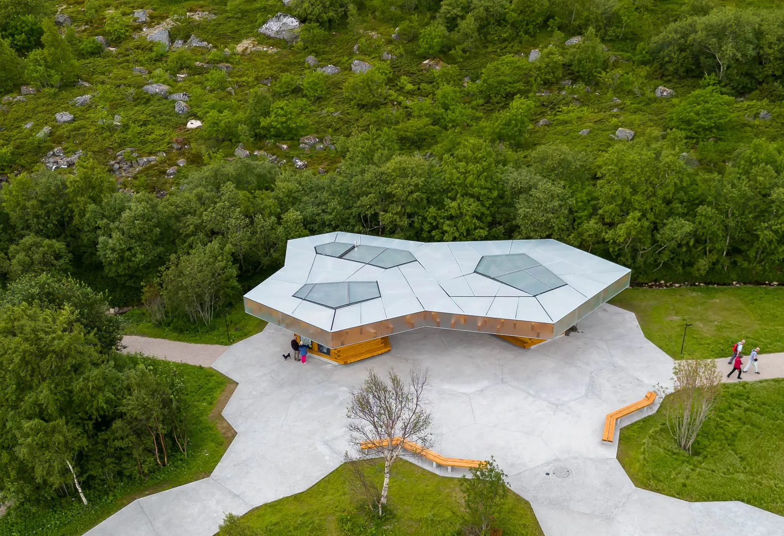 Visitor pavilion integrated into a natural landscape, featuring an angular roof structure, daylighting skylights, accessible public spaces, and carefully designed connections to surrounding recreational trails.