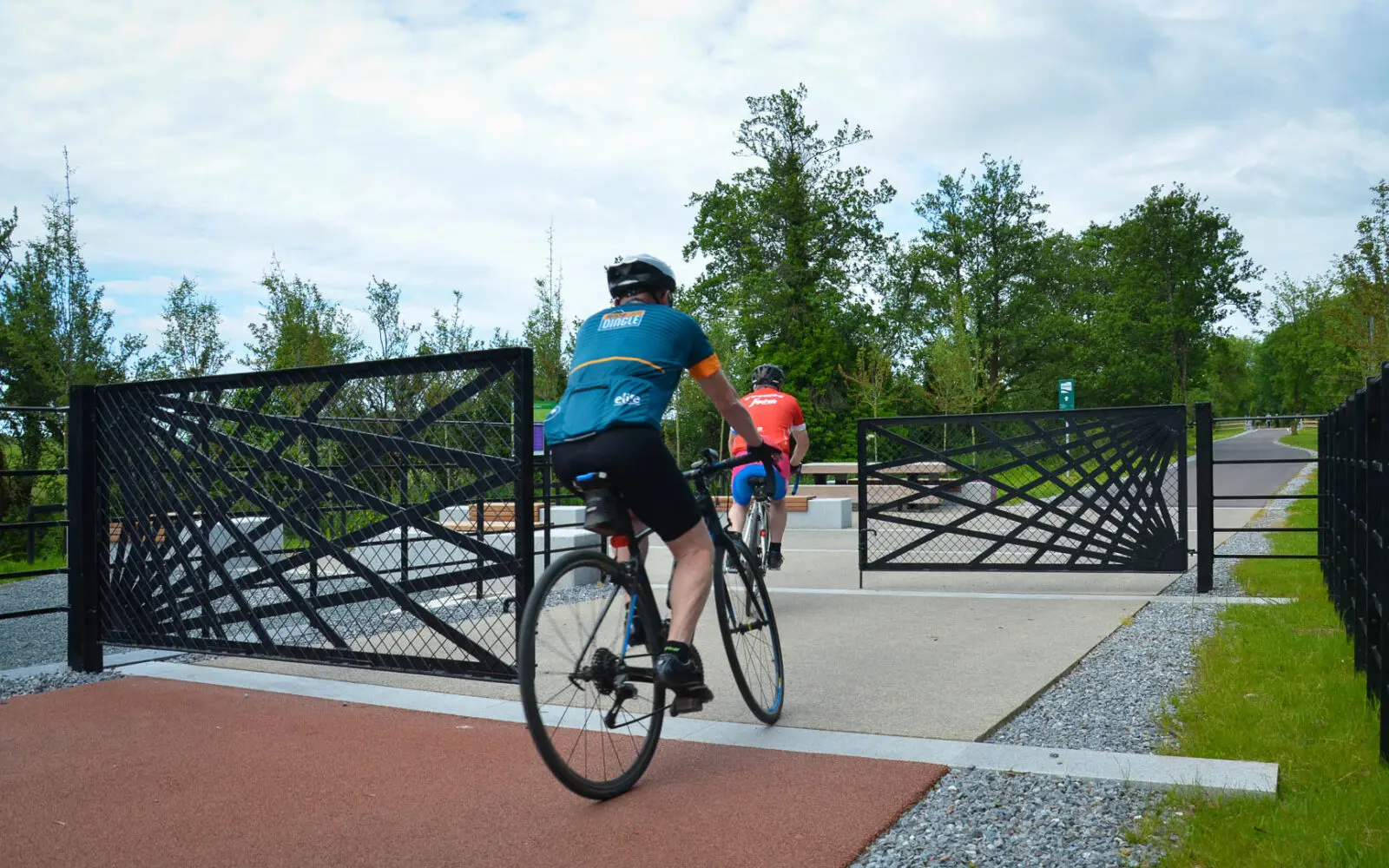 Active mobility corridor with cycling infrastructure, sculptural gateway elements, integrated seating, and native planting, designed to enhance connectivity and public realm quality.